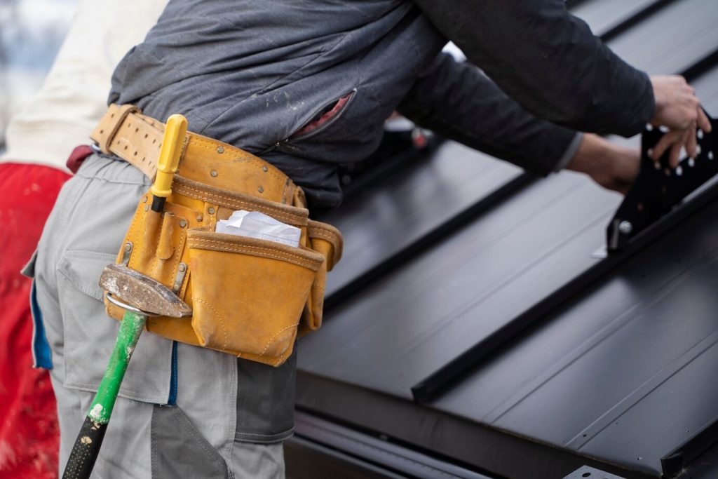 Roofer with tools on a metal roof